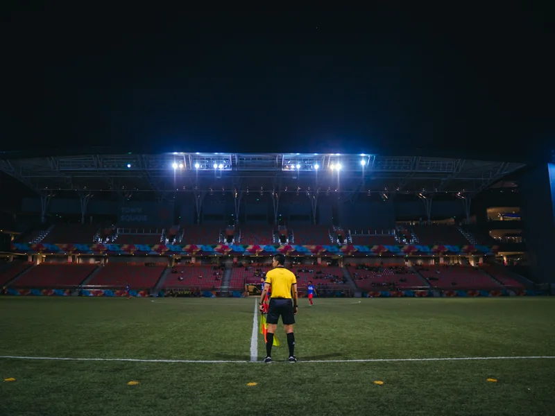 Neon-lit cricket pitch set up for a night match with DJ